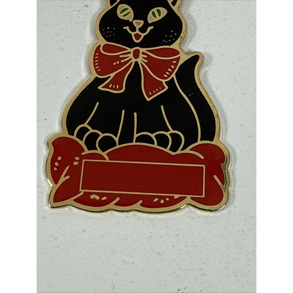 Black cat enamel keychain with gold-toned metal accents and a red bow